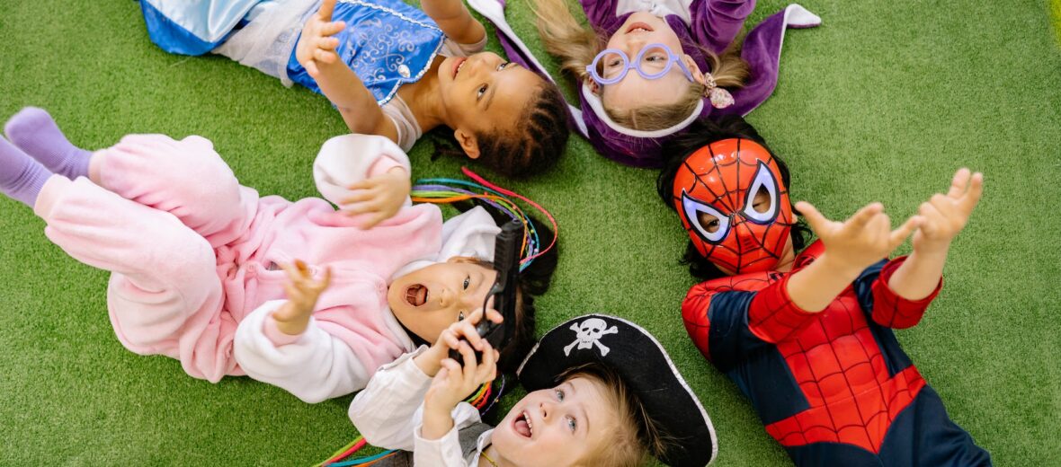 children lying on green carpet wearing different costumes
