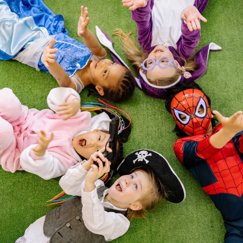 children lying on green carpet wearing different costumes