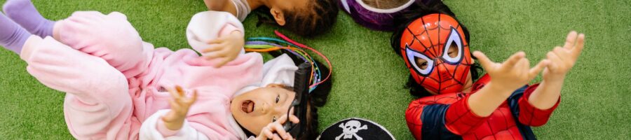 children lying on green carpet wearing different costumes