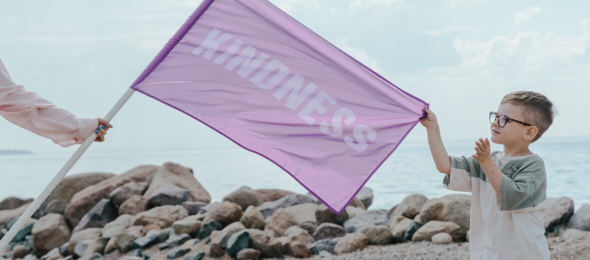a young boy holding a purple flag