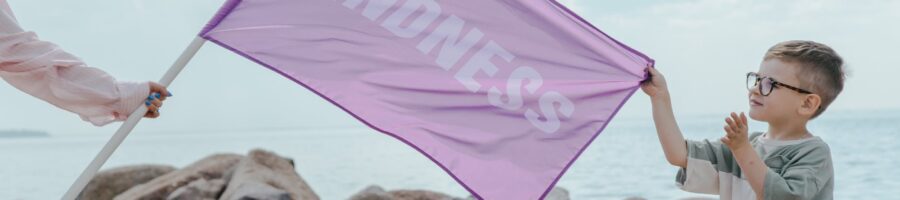 a young boy holding a purple flag